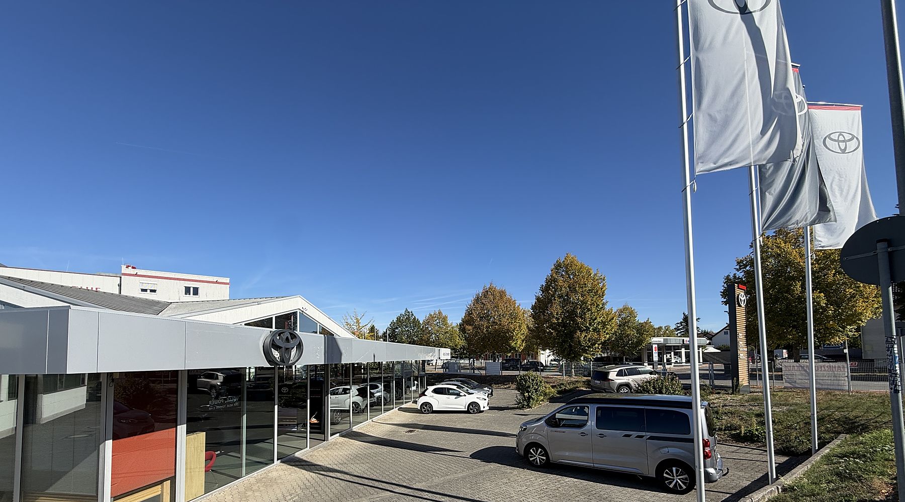 Gebäude von Auto Schneider in Bensheim mit Toyota-Fahnen und Fahrzeugen auf dem Hof